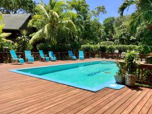 桑迪湾Tropical Treehouse的一个带蓝色椅子的木制甲板上的游泳池