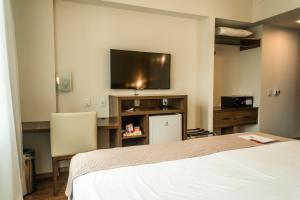 帕罗卡Firenze Business Hotel的一间卧室配有一张床和一台平面电视