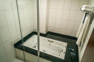 帕罗卡Firenze Business Hotel的玻璃门淋浴中的浴缸