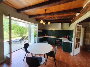 Saint-Bazile-de-MeyssacMaison d'amis du Manoir de Saint-Bazile的厨房配有绿色橱柜和桌椅