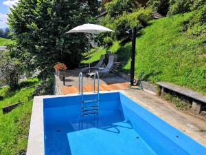 海利根舒文迪Schwendi-Blueme的蓝色的游泳池,配有遮阳伞和椅子