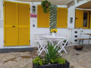 科维良Serra da Estrela Guest House的黄色门楼前的白色桌椅