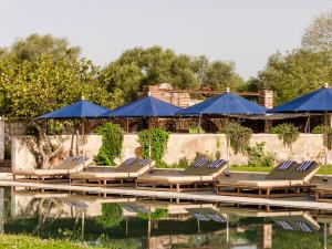 蒙萨拉什圣洛伦索巴洛卡酒店的游泳池旁的一排躺椅和蓝伞