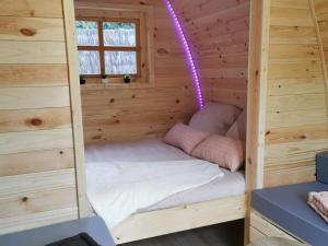LanthenayLes Pod Atypique de Sologne - Spa Privatif - Zoo de Beauval的小木屋内的一张小床,拥有紫色的光线