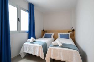 大加那利岛拉斯帕尔马斯Canteras Urban Beach的配有蓝色窗帘的客房内的两张床