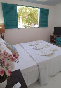 塔曼达雷Chalés Jardins dos Cajueiros的卧室配有白色的床和窗户