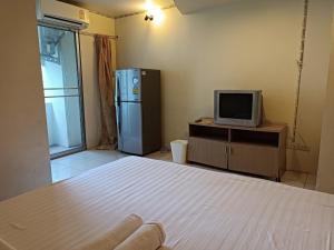 曼谷OYO 75417 Grandview Condominia的客房设有1张床、1台电视和1台冰箱。