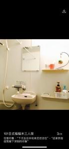 东京東洋の家-畳み部屋小庭園的白色的浴室设有水槽和镜子