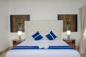 龙目岛库塔Matahari Inn Kuta Lombok的卧室配有带蓝色枕头的大型白色床