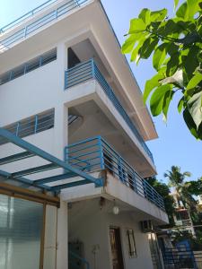 达波林Sai Leela Guest House的白色的房子,上面有蓝色的阳台