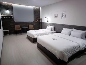 平泽市Hi& Hotel的酒店客房设有两张床和投影屏幕
