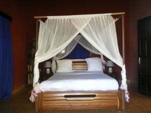 图利亚拉Bohobé Naboty的卧室配有带白色床单和枕头的天蓬床。