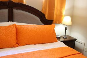 阿伯茨福德2-Bedroom basement suite with a separate entrance.的一张带橙色枕头的床和一张带台灯的桌子