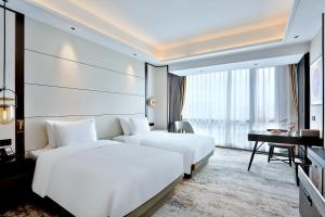 义乌银都酒店 Yandoo Hotel的配有书桌和卧室的酒店客房内的两张床