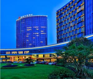 义乌银都酒店 Yandoo Hotel的一座高大的建筑,前面有汽车停放