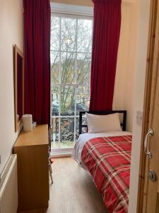 伦敦27 Argyle Square的一间卧室配有一张带红色窗帘的床和一扇窗户