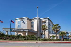 加尔维斯敦Clarion Pointe Galveston Seawall的街道前方有棕榈树的建筑
