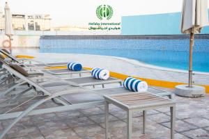迪拜Holiday International Hotel Embassy District的游泳池旁的一排椅子
