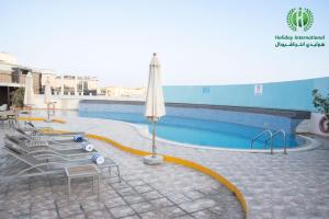 迪拜Holiday International Hotel Embassy District的一个带椅子和遮阳伞的游泳池