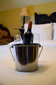 蒙克顿Magnetic Hill Winery的床上的一瓶葡萄酒和两杯水桶