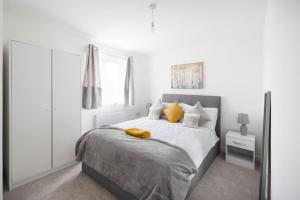 Fortified Three Bedroom Home Bristol的白色卧室配有一张带黄色枕头的大床