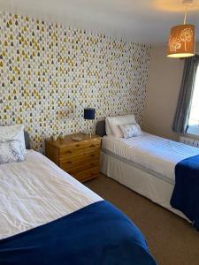 甘尼斯莱克3 Bedroom Lodge with hot tub on lovely quiet holiday park in Cornwall的一间卧室配有两张床和一张带台灯的桌子