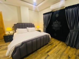 拉瓦尔品第Holidazzle Serviced Apartments Bahria Town的一间卧室配有一张大床和黑色床头板