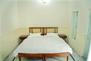 范兰德凡Shree Krishna Bhakti Ashram的一间卧室配有一张带白色床单的床和两个窗户。