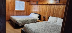 托菲诺Meares Vista Inn的客房设有两张床、一个窗户和木墙