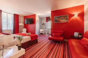莱塞齐耶德泰阿克Hostellerie du Passeur - Hôtel & Restaurant - Climatisation et Piscine chauffée的一间酒店客房,拥有红色的墙壁,配有一张床和一张沙发