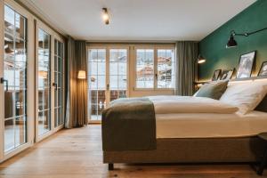 格林德尔瓦尔德Hotel Fiescherblick的一间卧室设有一张大床和绿色的墙壁