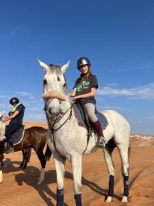 ShāhiqCrescent Desert Private Camp的沙漠中骑白马的女人