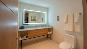 梅里达Holiday Inn & Suites - Merida La Isla, an IHG Hotel的一间带水槽、镜子和卫生间的浴室