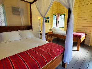 UnitedvilleLower Dover Jungle Lodge & Maya Ruins的一间卧室配有一张床、一张桌子和一张四柱床。