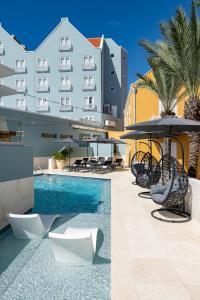 威廉斯塔德Harbor Hotel & Casino Curacao的一座带椅子和遮阳伞的游泳池位于一座建筑旁边