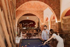 拉戈斯德莫雷诺Hacienda Sepulveda Hotel & Spa的男人和女人在餐厅里打台球