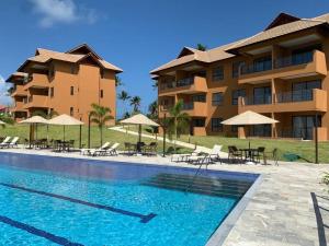 塔曼达雷ECO RESORT PRAIA DOS CARNEIROS - NOVÍSSIMO的一个带椅子和遮阳伞的游泳池的度假酒店
