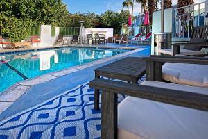 棕榈泉Inn at Palm Springs的游泳池旁设有长椅和椅子