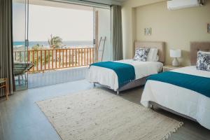 维加伊托Kokoa Hotel Vichayito的一间带两张床的卧室和一个海景阳台