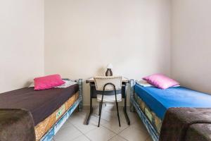 瓜鲁雅Apartamento encantador no Guarujá, praia da Enseada - Apenas 600m da praia !的客房设有两张床和一张带椅子的桌子。