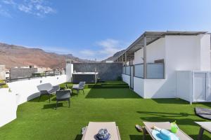 圣尼科拉斯村Apartamento Starlight La Aldea I的屋顶露台拥有绿色的草地和白色的墙壁