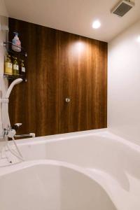 福冈TEN APARTMENT HOTEL的一间带浴缸和大镜子的浴室