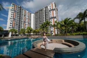 关丹Timurbay Beachfront by Perfect Host的站在一座有建筑物的游泳池旁的比基尼的女人