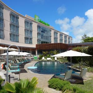 蓝海湾Holiday Inn Mauritius Mon Trésor, an IHG Hotel的一个带游泳池、椅子和遮阳伞的酒店