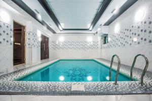 塔什干Manifa Hotel的白色浴室内的游泳池,配有浴缸