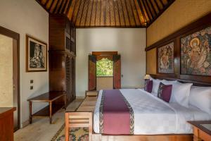 乌布Puri Saraswati Dijiwa Ubud的一间卧室配有一张床、一张桌子和一个窗户。
