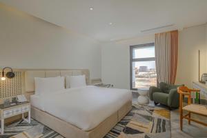吉达Ewaa Express Hotel - Al Shati的卧室配有一张白色大床和一把椅子