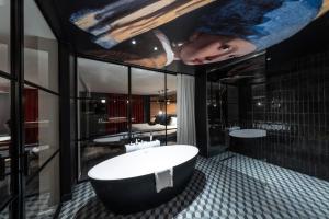 伯尼索米诺格Hôtel Baud - Teritoria的浴室设有大浴缸,天花板上装饰有绘画作品