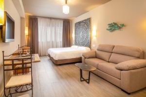 塞维利亚Apartamentos Sevilla Este by QHotels的客厅配有沙发和1张床