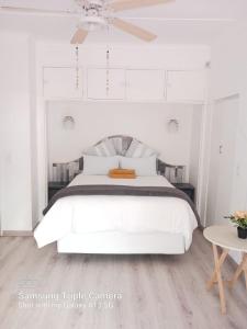 勒斯滕堡Pythons Guest Lodge的白色的卧室配有白色的床和一张桌子